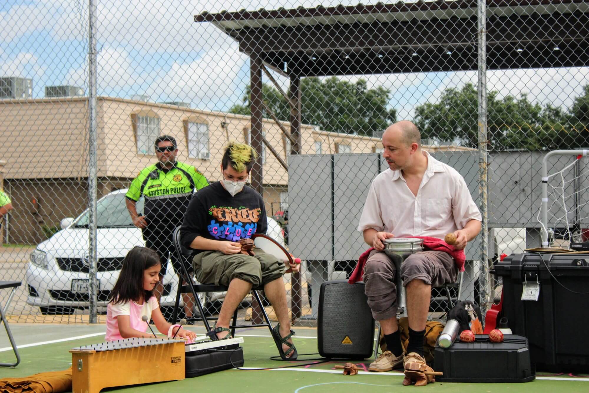Neighbours of all ages seated in a circle with drums and percussion instruments