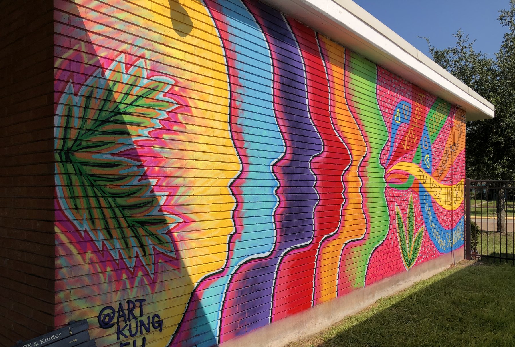 A long school wall painted with rainbow stripes and faces in profile