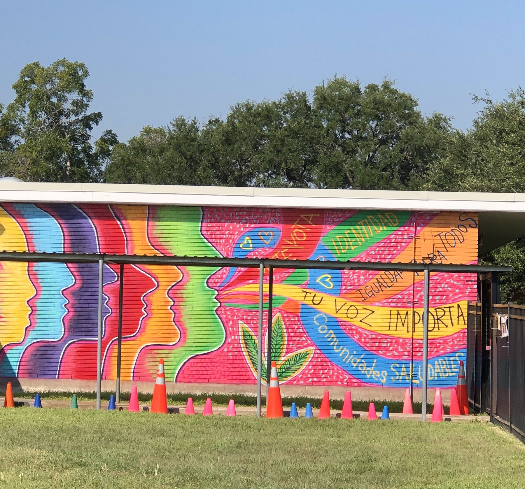 A school building painted with a wide rainbow mural reading Tu voz importa