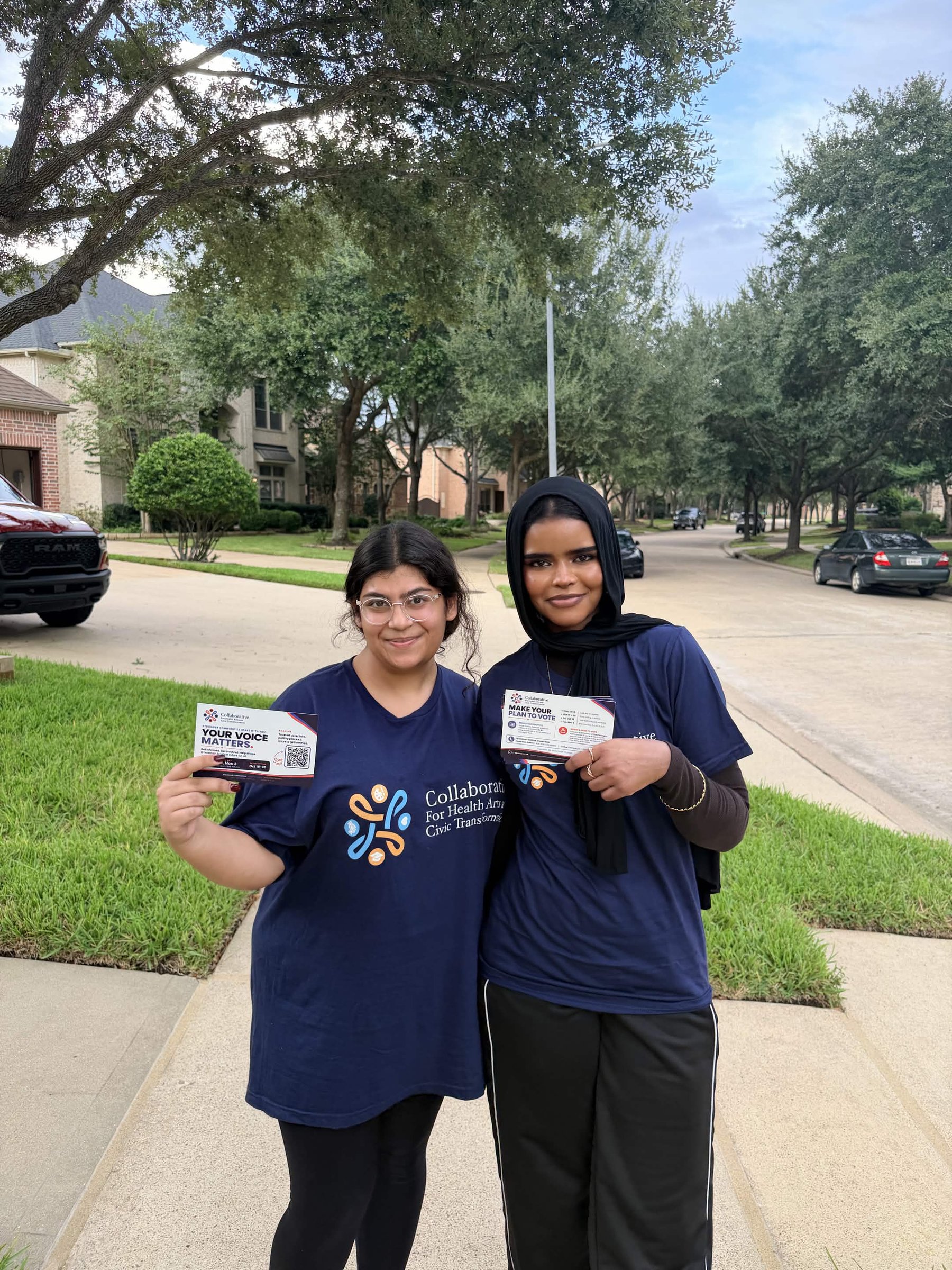 Two canvassers in Collaborative t-shirts holding voter information cards on a residential street