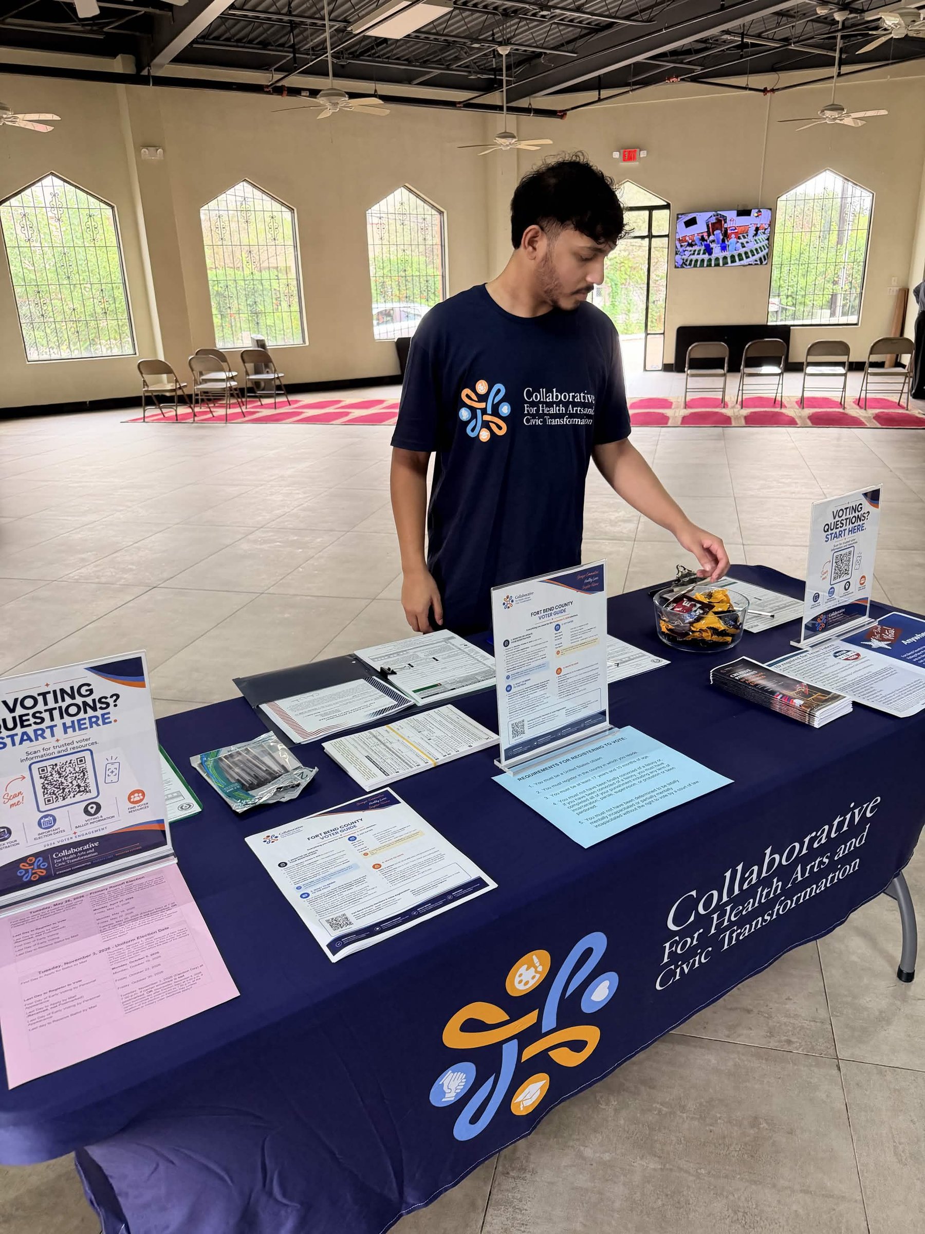 A volunteer setting up a Collaborative table with voter guides and registration forms