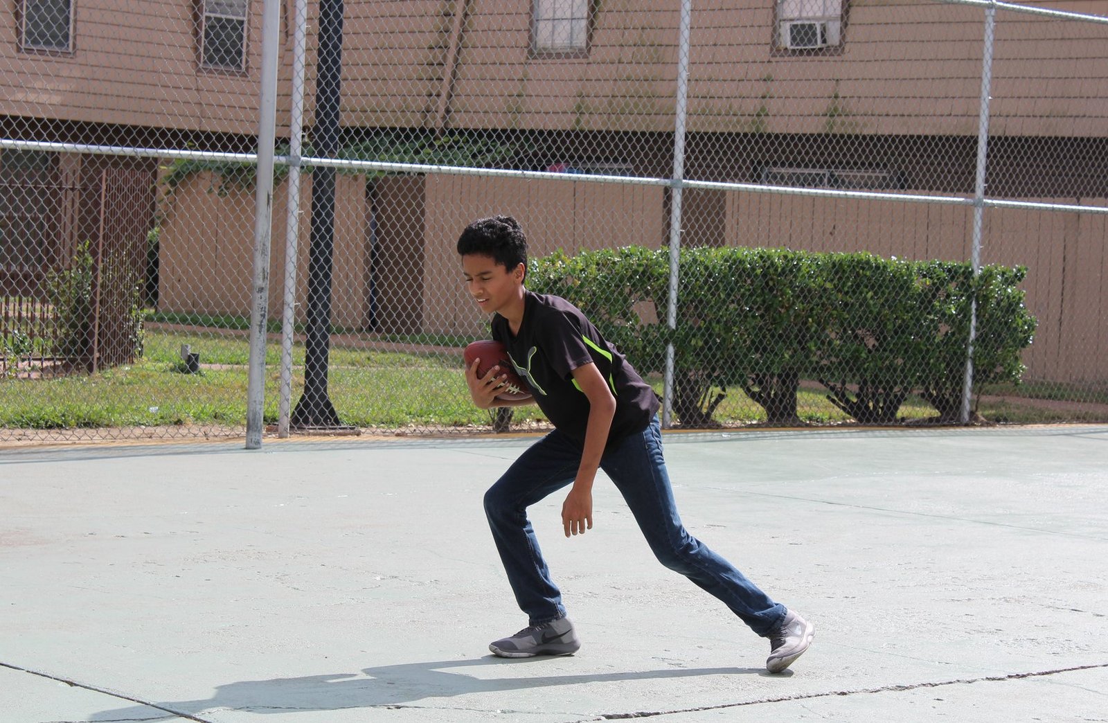 A young person running with a ball during an outdoor youth program session