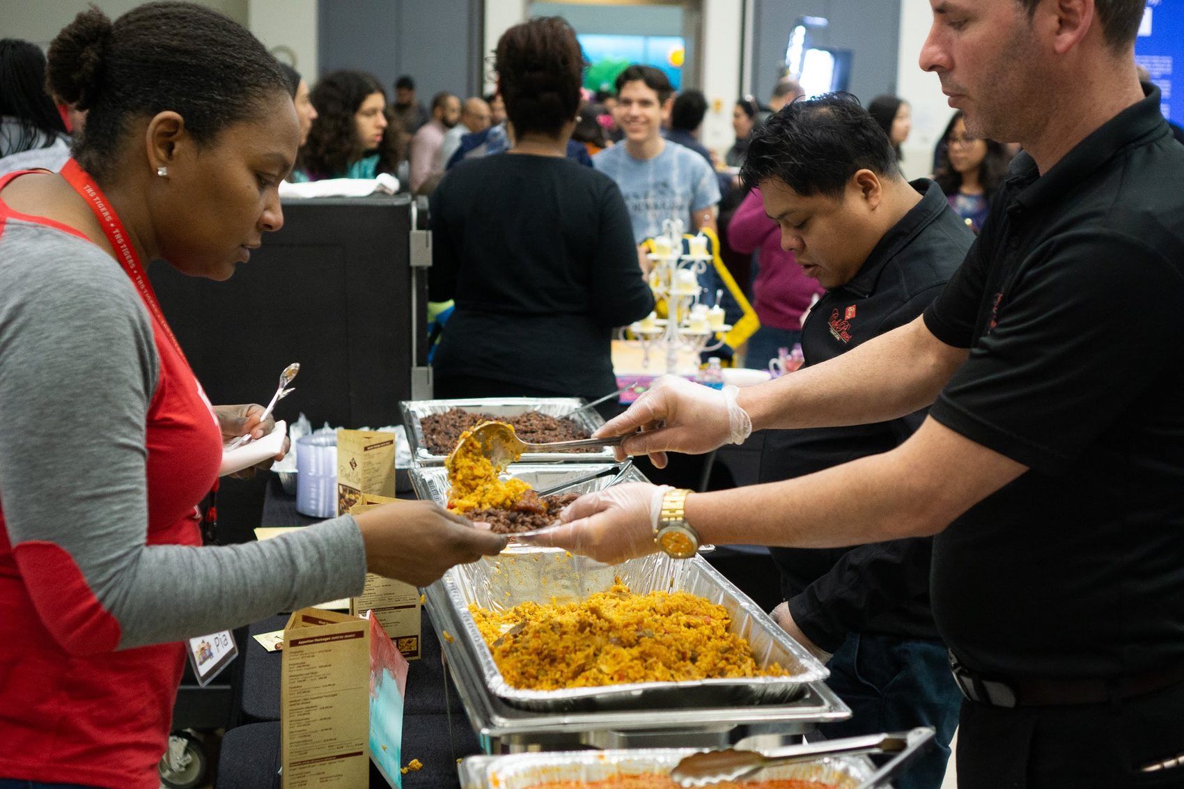 Volunteers serving food from trays at a community event