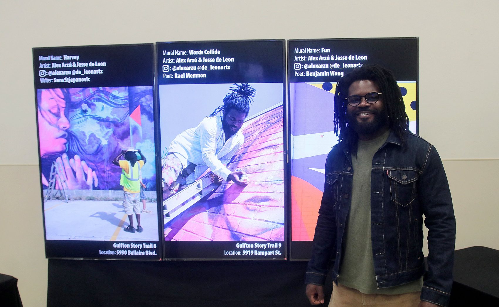 Display screens showing mural names, artists and locations, with a visitor alongside